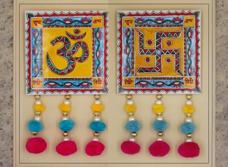 Traditional wall hanging featuring intricate patterns with a minimal lotus, 'aum,' and swastik as the central designs, adorned with colorful beads.