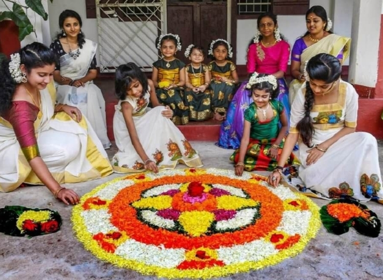 Colorful pookalam rangoli featuring intricate floral patterns, vibrant hues of yellow, pink, and green, set on a white background.