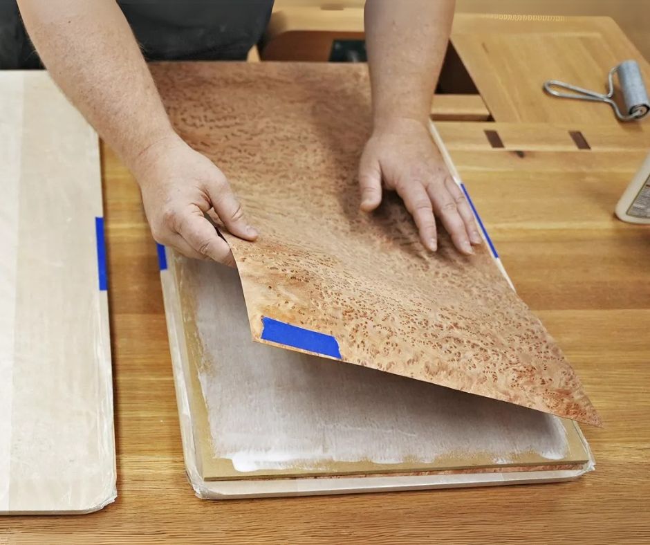 Application of glue to veneer sheet and the substrate and carefully positioning the veneer sheet on the substrate